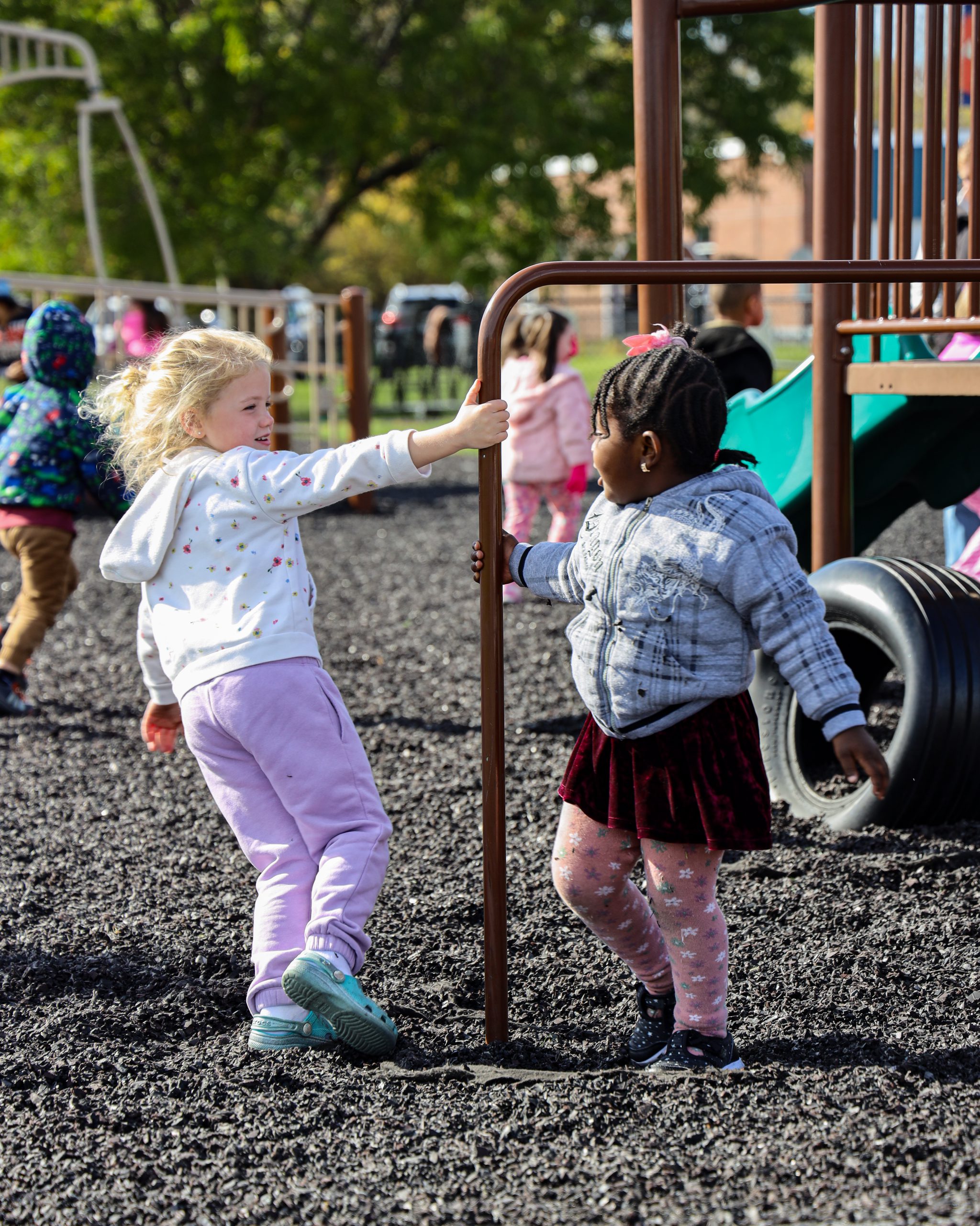 Two young girls play together at recess.