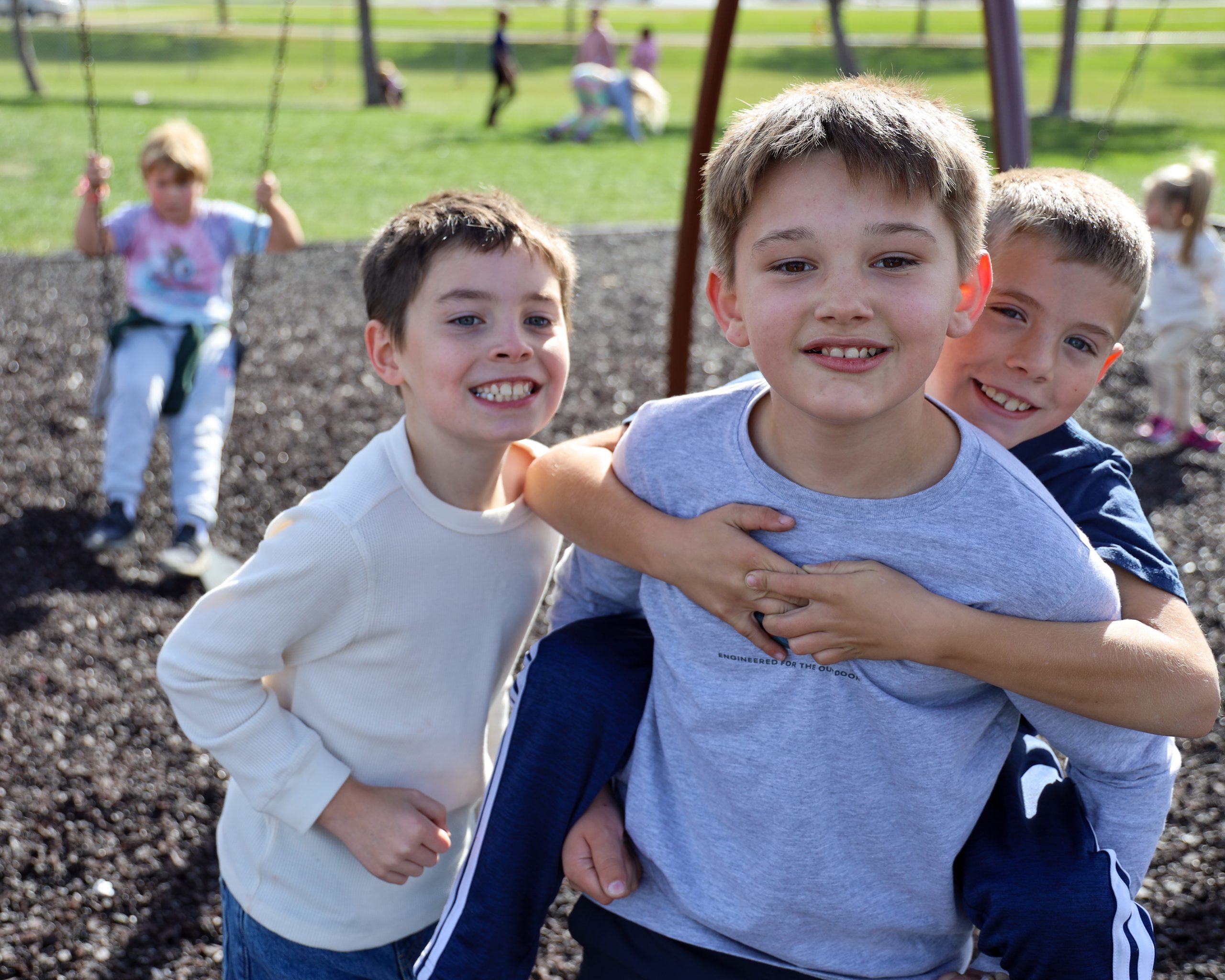 Three elementary boys smiling at the camera.