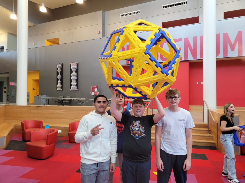 Students hold large geometric shape, as they take part in SUNY Potsdam's STEM day. 