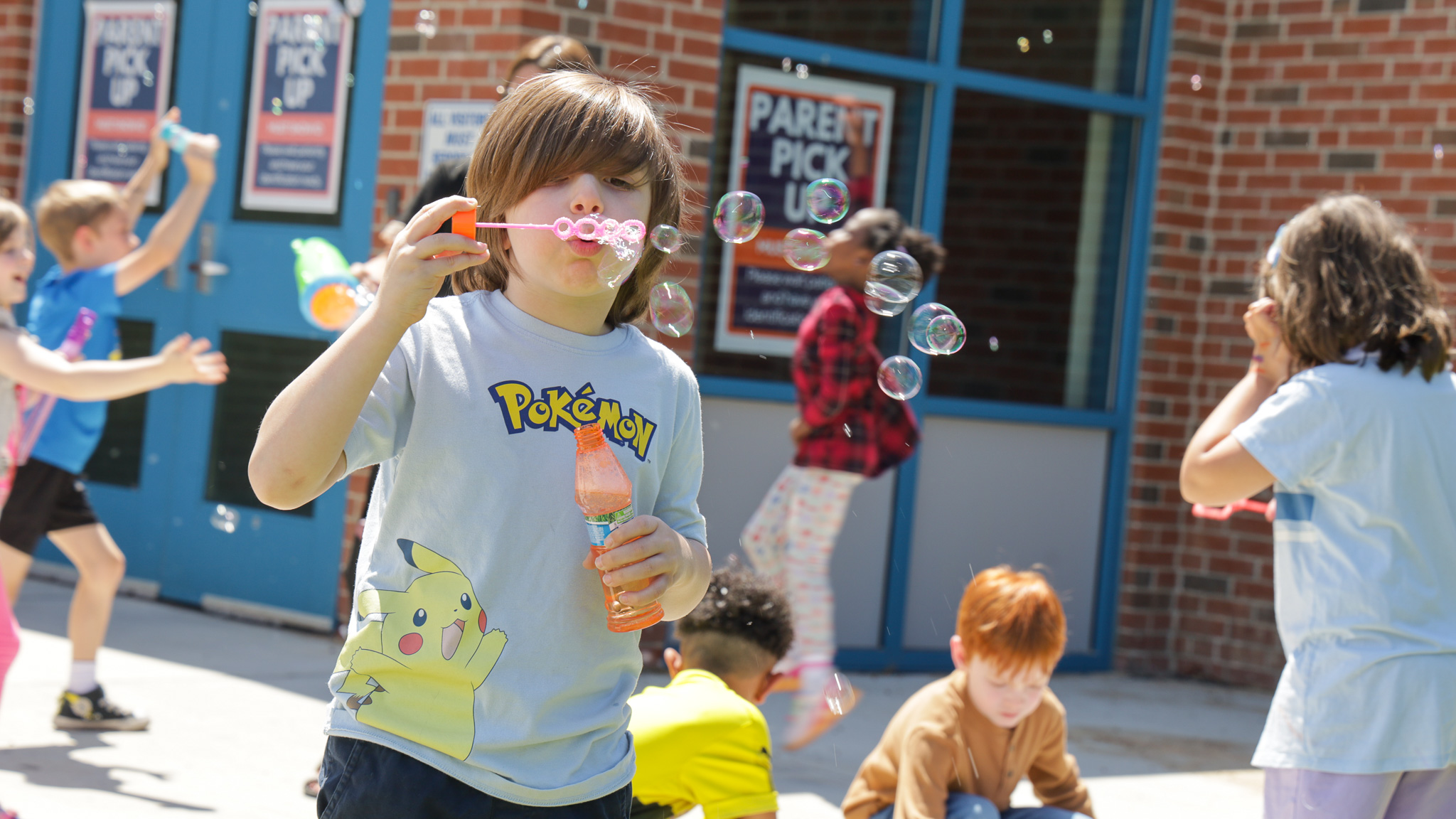 Elementary boy blows bubbles outside 