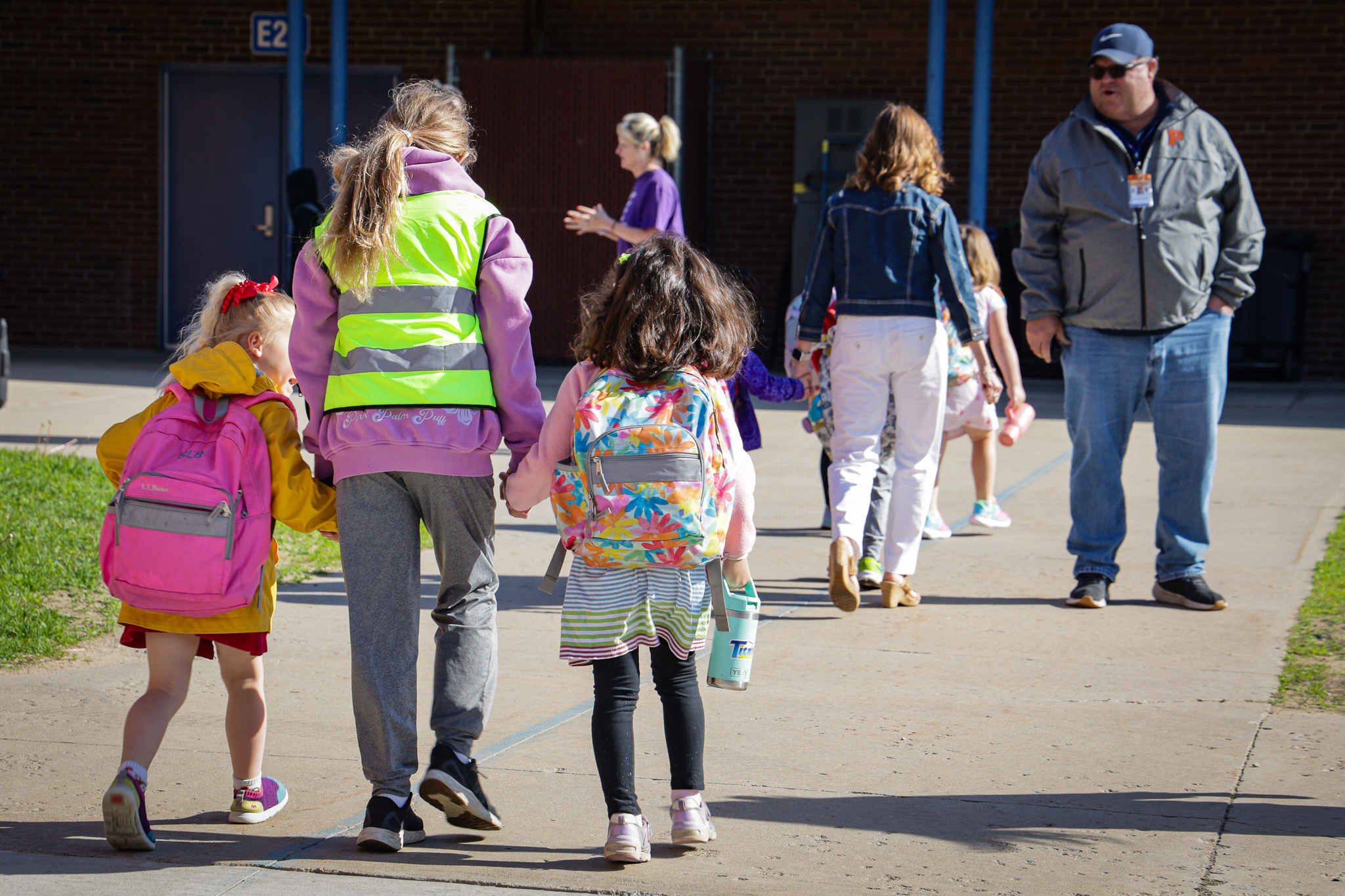 Elementary girls hold hands with crossing guard