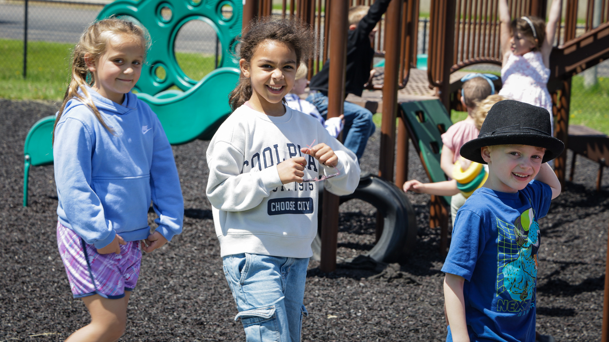 Elementary  student smiles big while playing outside on playground. 